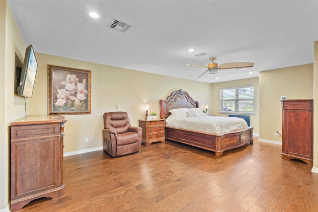 bedroom with ceiling fan, light wood-type flooring, and a textured ceiling