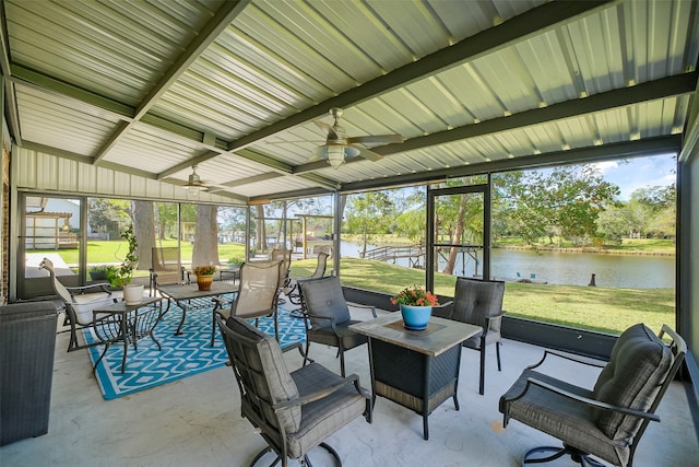 sunroom featuring lofted ceiling with beams, ceiling fan, and a water view