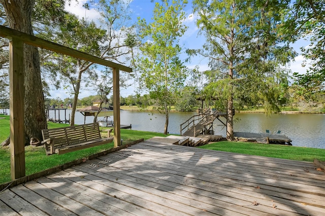 wooden deck featuring a yard, a water view, and a dock