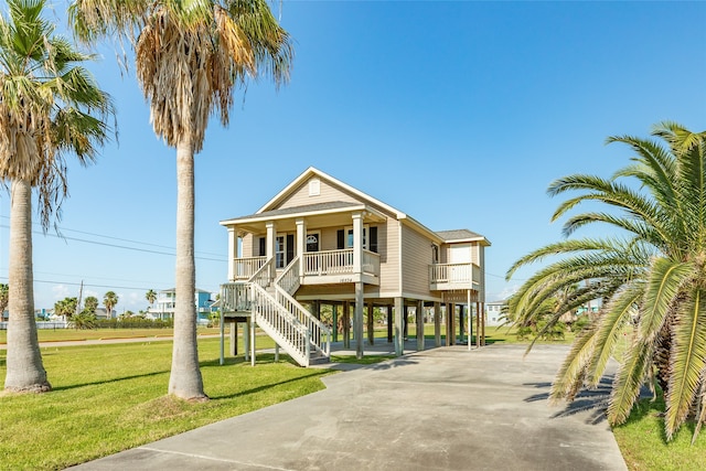 coastal home featuring a carport, a porch, and a front lawn