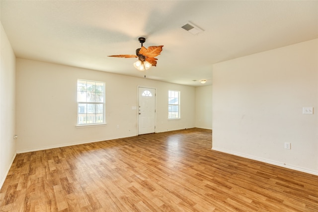 empty room featuring light wood-type flooring, a healthy amount of sunlight, and ceiling fan