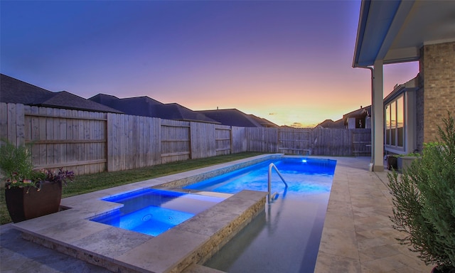 pool at dusk with a patio and an in ground hot tub