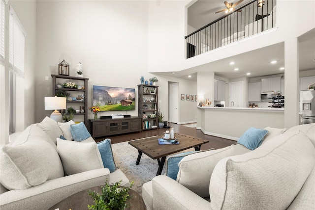 living room featuring a high ceiling, ceiling fan, and hardwood / wood-style floors