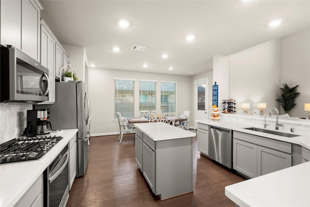 kitchen featuring appliances with stainless steel finishes, dark wood-type flooring, sink, a center island, and gray cabinets