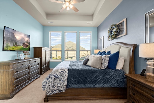 carpeted bedroom featuring a tray ceiling and ceiling fan