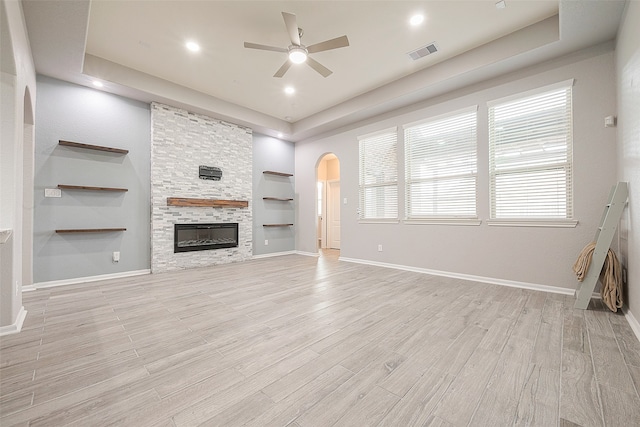 unfurnished living room with light hardwood / wood-style floors, a tray ceiling, and ceiling fan