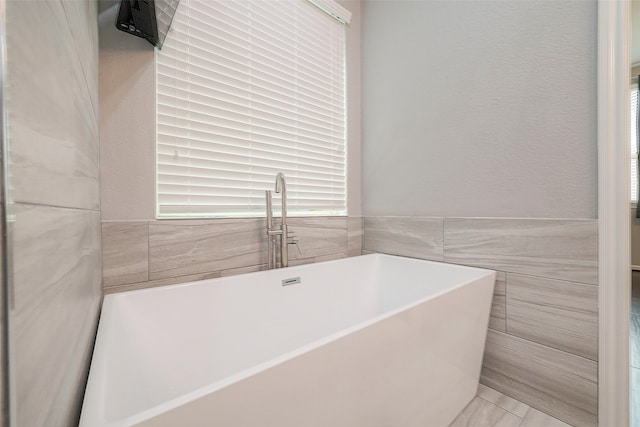 bathroom with a bath and tile walls