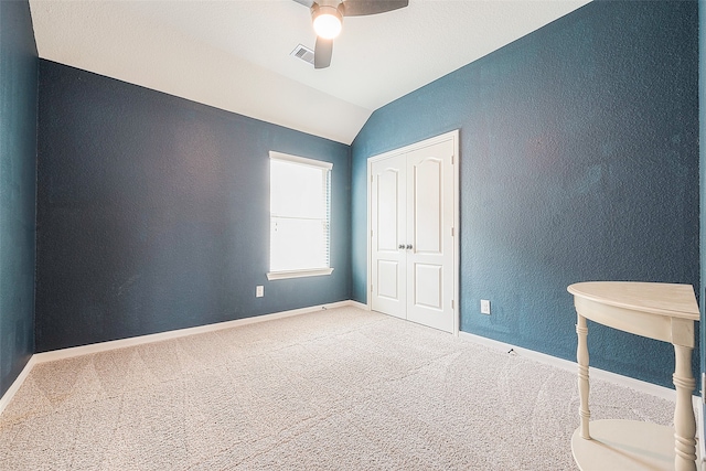 unfurnished bedroom with a closet, ceiling fan, carpet flooring, and vaulted ceiling