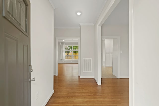 hallway featuring ornamental molding and light hardwood / wood-style flooring