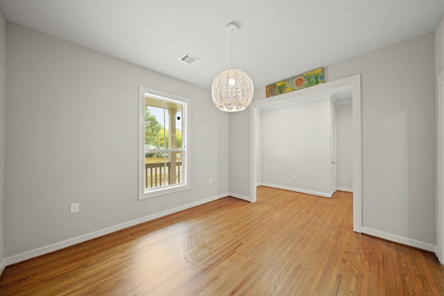 unfurnished room featuring an inviting chandelier and hardwood / wood-style floors