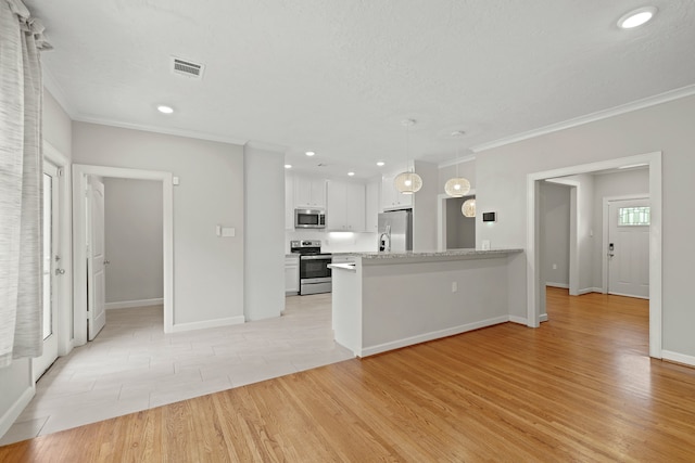 kitchen featuring appliances with stainless steel finishes, light hardwood / wood-style flooring, white cabinetry, and decorative light fixtures