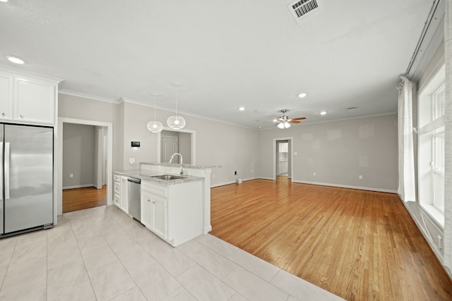 kitchen with white cabinets, appliances with stainless steel finishes, light stone countertops, light hardwood / wood-style floors, and sink