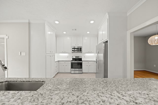 kitchen with white cabinets, light stone countertops, light wood-type flooring, sink, and stainless steel appliances