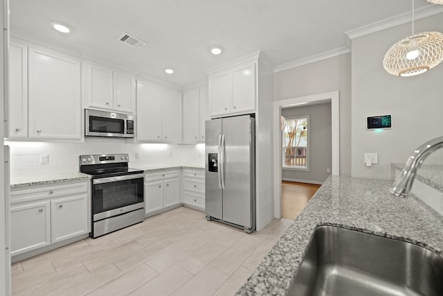 kitchen with white cabinets, hanging light fixtures, ornamental molding, sink, and stainless steel appliances