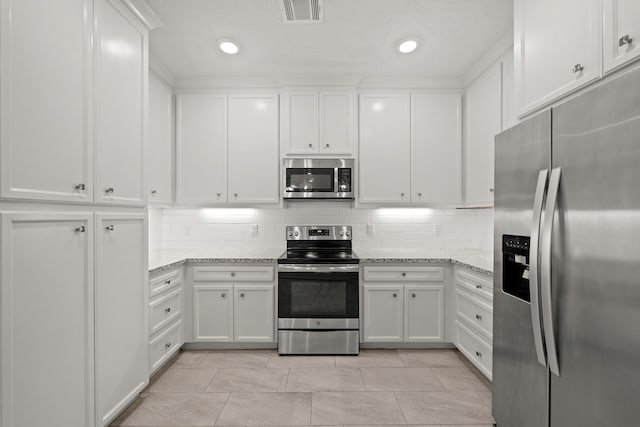 kitchen featuring light stone counters, appliances with stainless steel finishes, backsplash, and white cabinets