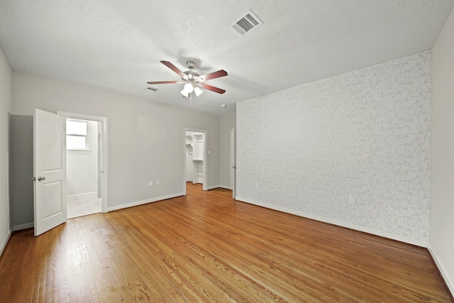 unfurnished room with a textured ceiling, wood-type flooring, and ceiling fan