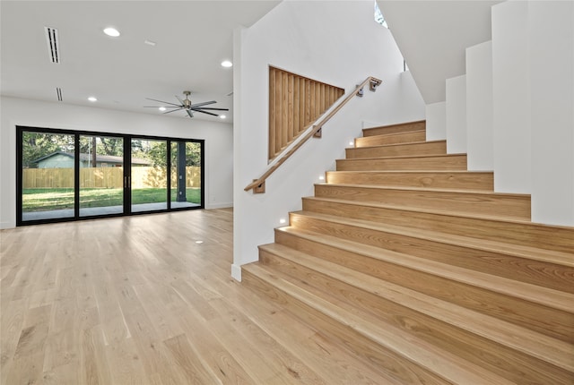 staircase with ceiling fan and hardwood / wood-style floors