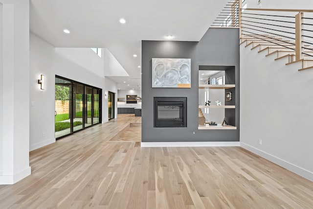 unfurnished living room featuring a towering ceiling and light hardwood / wood-style floors