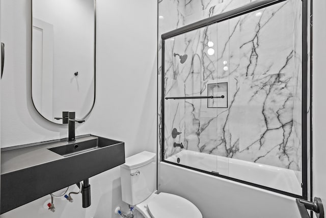 bathroom with toilet and bath / shower combo with glass door