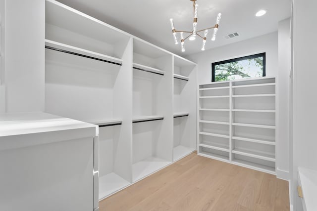 walk in closet with an inviting chandelier and light wood-type flooring