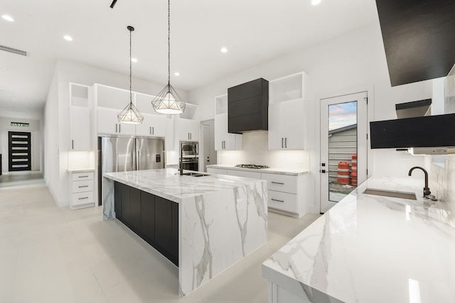 kitchen featuring a large island, sink, light stone countertops, decorative light fixtures, and custom exhaust hood