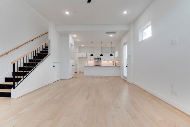 unfurnished living room with sink and light hardwood / wood-style flooring