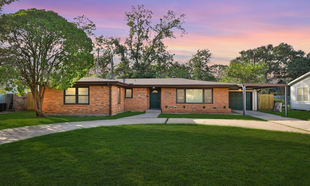 ranch-style home with a yard, a carport, and a garage