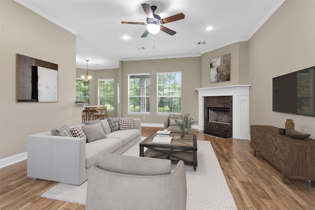 living room featuring a tiled fireplace, crown molding, and hardwood / wood-style flooring