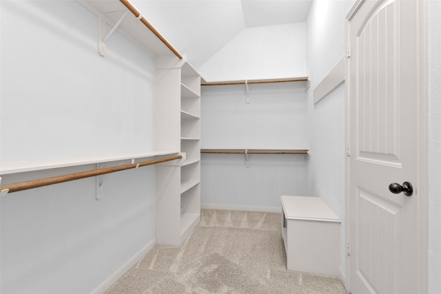 walk in closet featuring light carpet and lofted ceiling