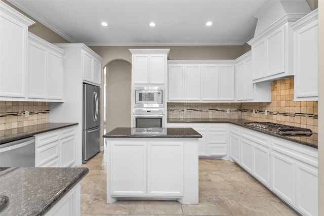 kitchen with decorative backsplash, crown molding, appliances with stainless steel finishes, and dark stone counters