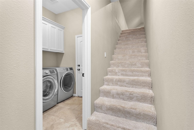 washroom featuring light tile patterned flooring, cabinets, and independent washer and dryer