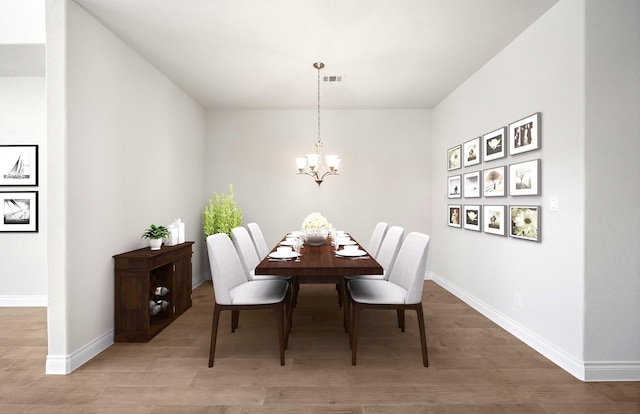 dining space with hardwood / wood-style flooring and an inviting chandelier