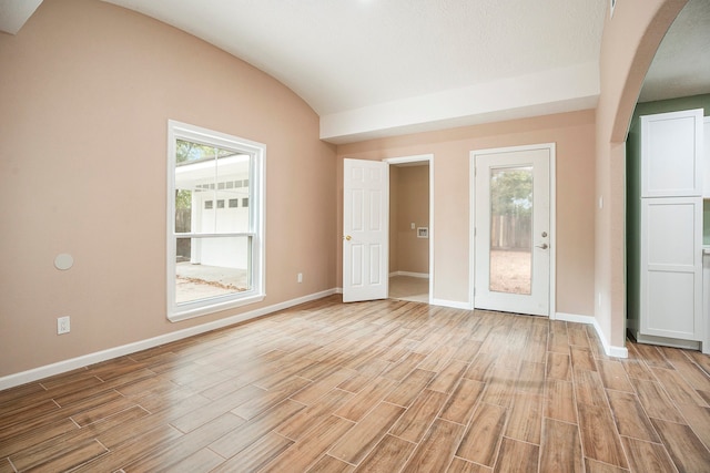 interior space with vaulted ceiling, a textured ceiling, a wealth of natural light, and light wood-type flooring