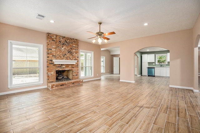 unfurnished living room featuring sink, a textured ceiling, light hardwood / wood-style floors, and ceiling fan