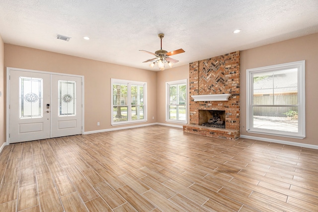 unfurnished living room featuring ceiling fan, a textured ceiling, light hardwood / wood-style flooring, and plenty of natural light