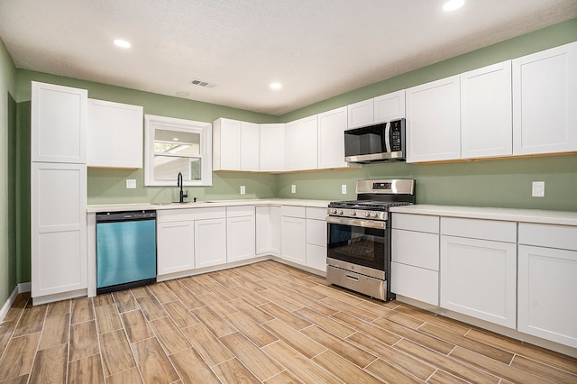 kitchen featuring light hardwood / wood-style flooring, white cabinetry, stainless steel appliances, and sink