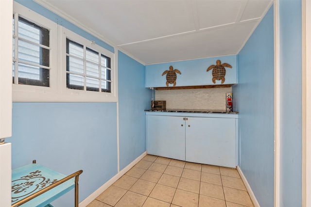 interior space with crown molding, backsplash, and light tile patterned floors