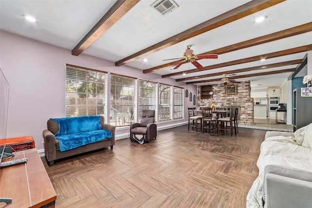 living room with parquet flooring, beam ceiling, a brick fireplace, and ceiling fan