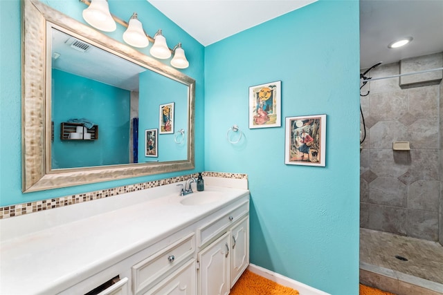 bathroom with a tile shower and vanity