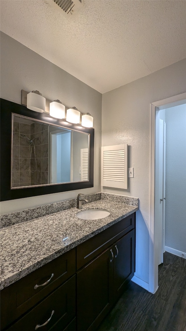 bathroom with vanity, wood-type flooring, a textured ceiling, and walk in shower