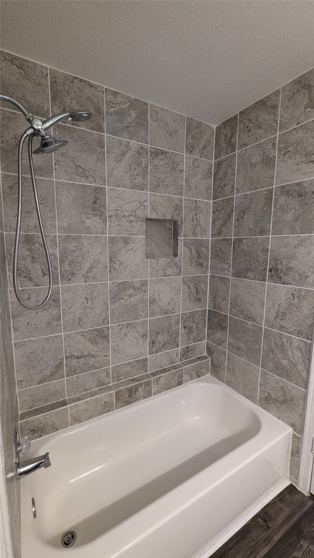 bathroom featuring tiled shower / bath, a textured ceiling, and hardwood / wood-style flooring