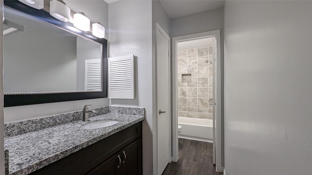 full bathroom featuring vanity, washtub / shower combination, hardwood / wood-style flooring, and toilet