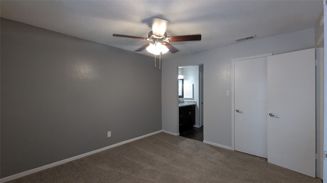 unfurnished bedroom with ensuite bath, carpet floors, a closet, and ceiling fan