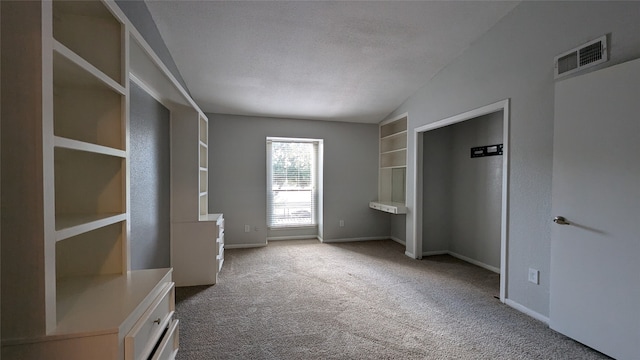 unfurnished bedroom with a textured ceiling, carpet, and vaulted ceiling