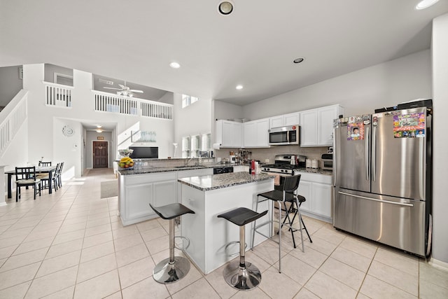 kitchen with a kitchen island, dark stone counters, white cabinetry, appliances with stainless steel finishes, and ceiling fan