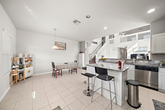 kitchen with dishwasher, hanging light fixtures, dark stone countertops, light tile patterned floors, and white cabinetry