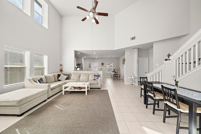 living room featuring a high ceiling, light tile patterned flooring, a healthy amount of sunlight, and ceiling fan