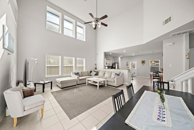 living room featuring a wealth of natural light, light tile patterned flooring, a towering ceiling, and ceiling fan