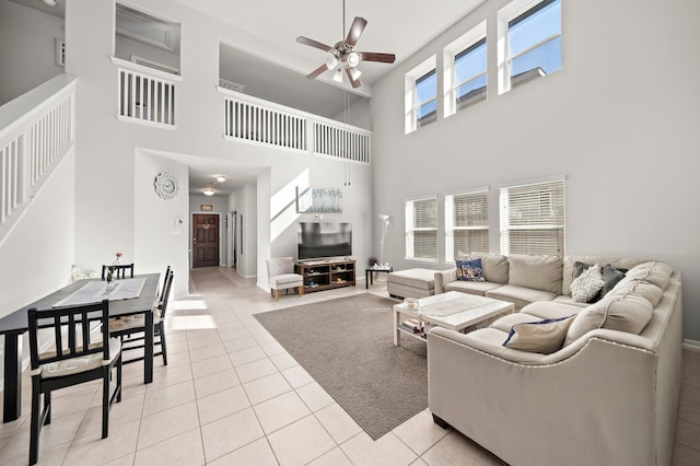 tiled living room featuring ceiling fan, a healthy amount of sunlight, and a high ceiling