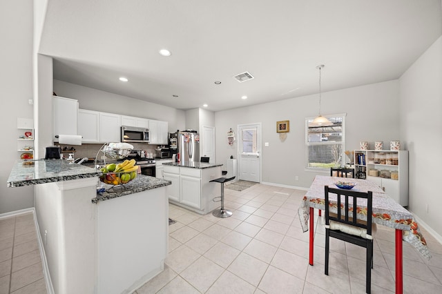 kitchen with appliances with stainless steel finishes, pendant lighting, backsplash, and white cabinets